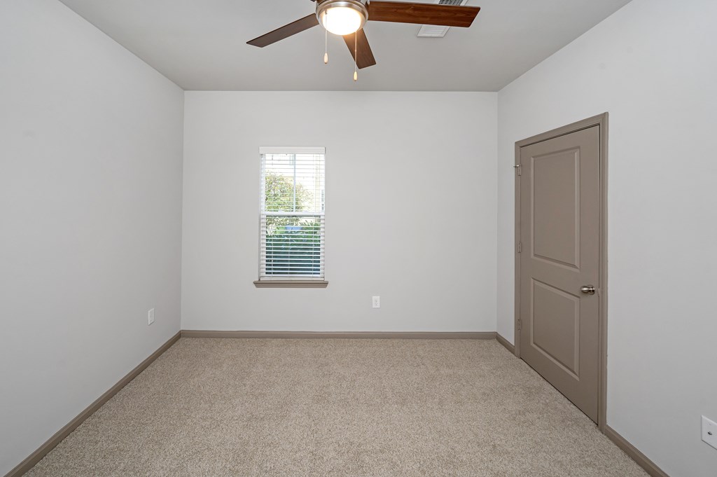 A room with a ceiling fan and a door.